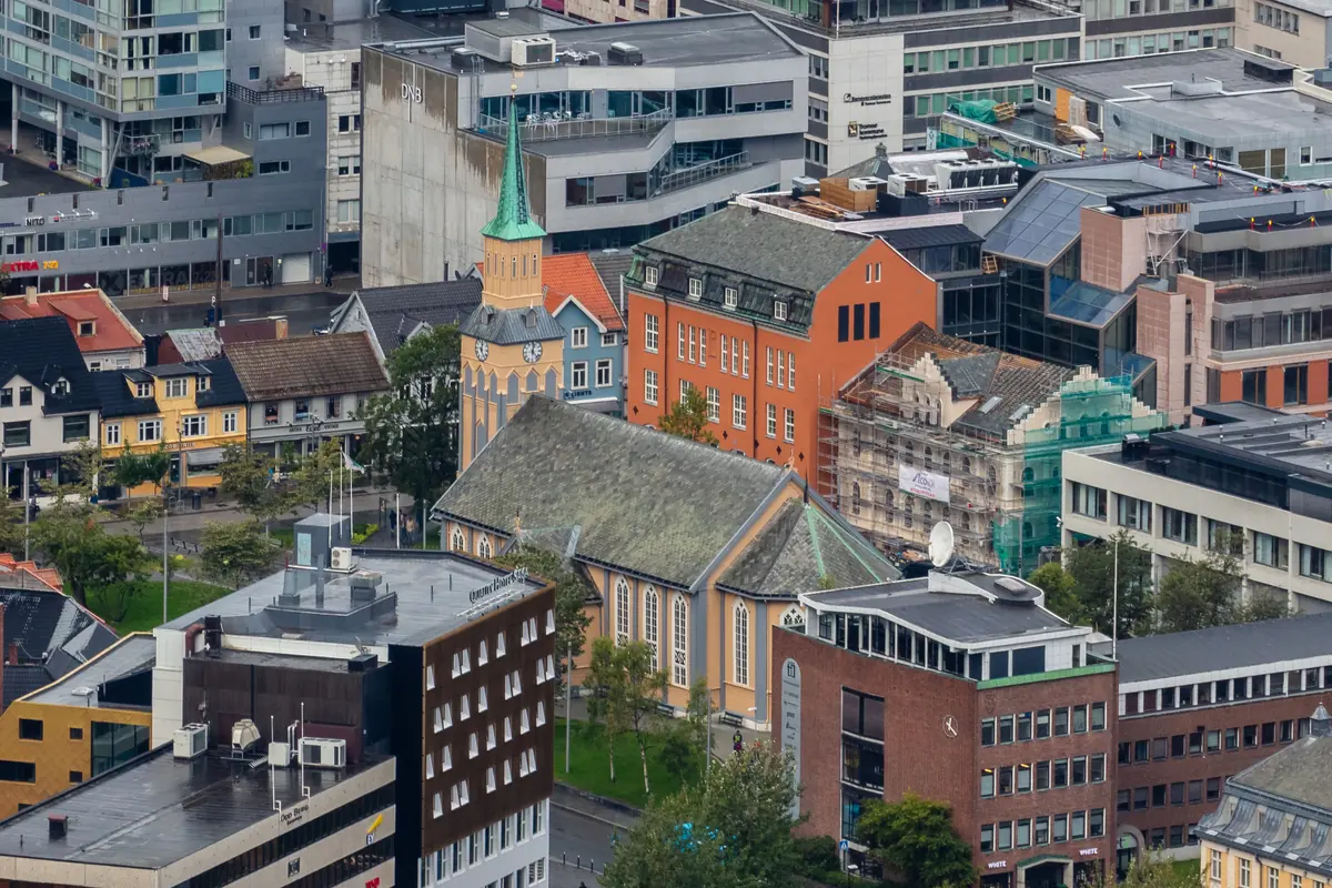 Tromsø Cathedral seen from above, a long wooden church with a grey roof and a green-capped tower among the buildings of the city centre