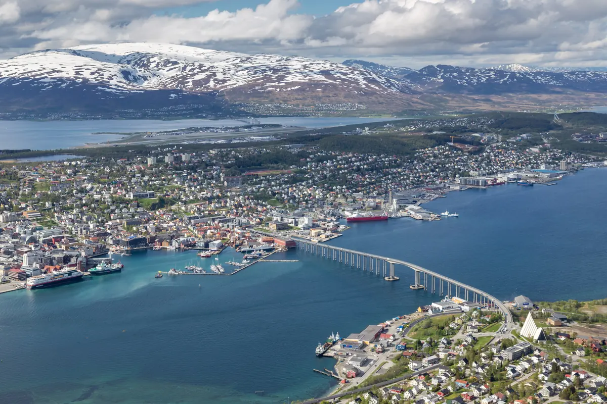 Aerial view of Tromsø with the island city, the long Tromsø Bridge across the strait and mountains behind